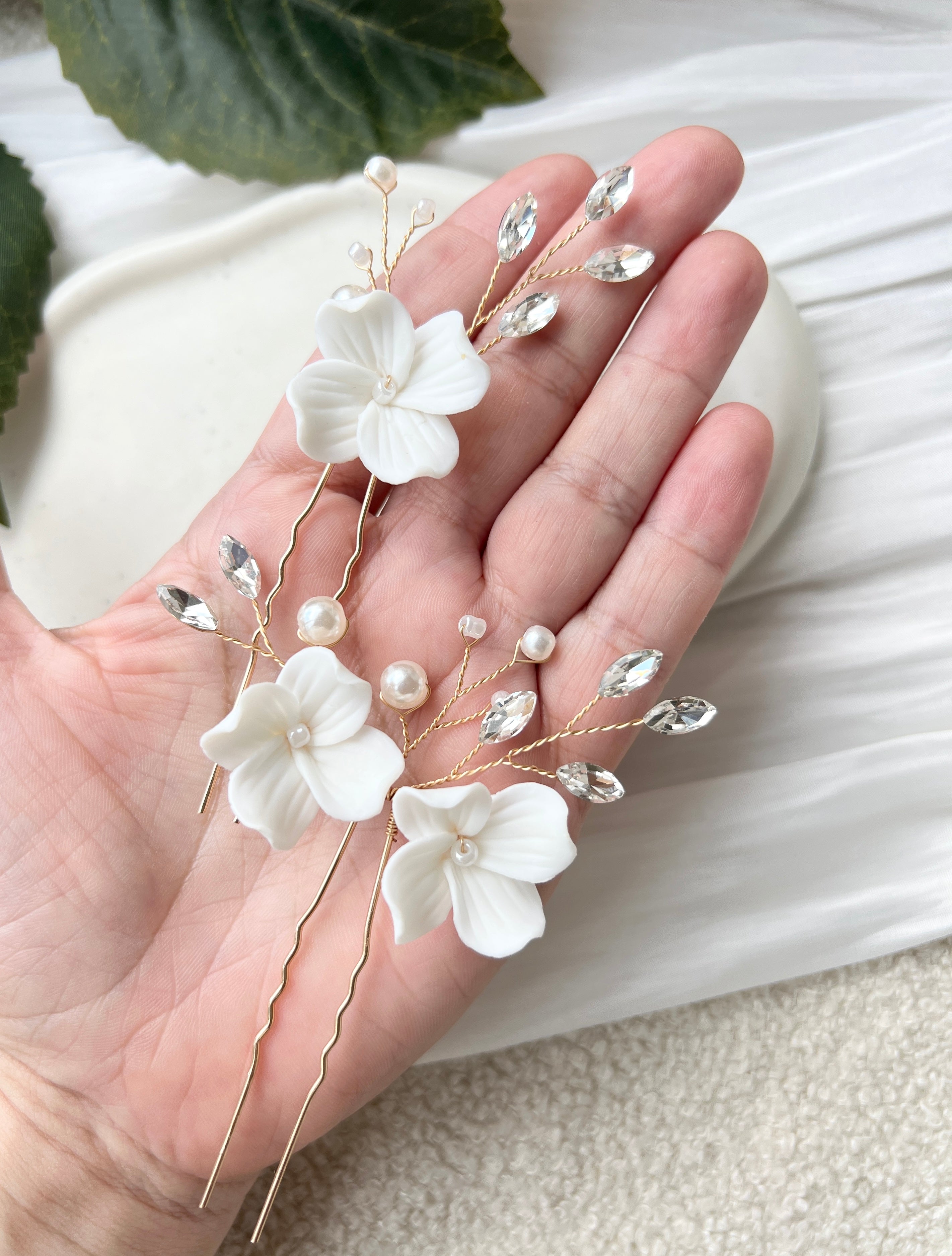 Feine Haarnadeln, Set 2 Stueck, Blumen aus Keramik, feiner goldener Schmuck, Haarschmuck fuer die Brautfrisur, weisser Bluetenschmuck, zarte Perlen und Strasssteine, eleganter Brautschmuck, moderner Perlenschmuck, luxurioeser Brauthaarschmuck, Perlenhaarschmuck, hochwertiger Hochzeitsschmuck, Schmuck Hochzeit, Weddinginspiration