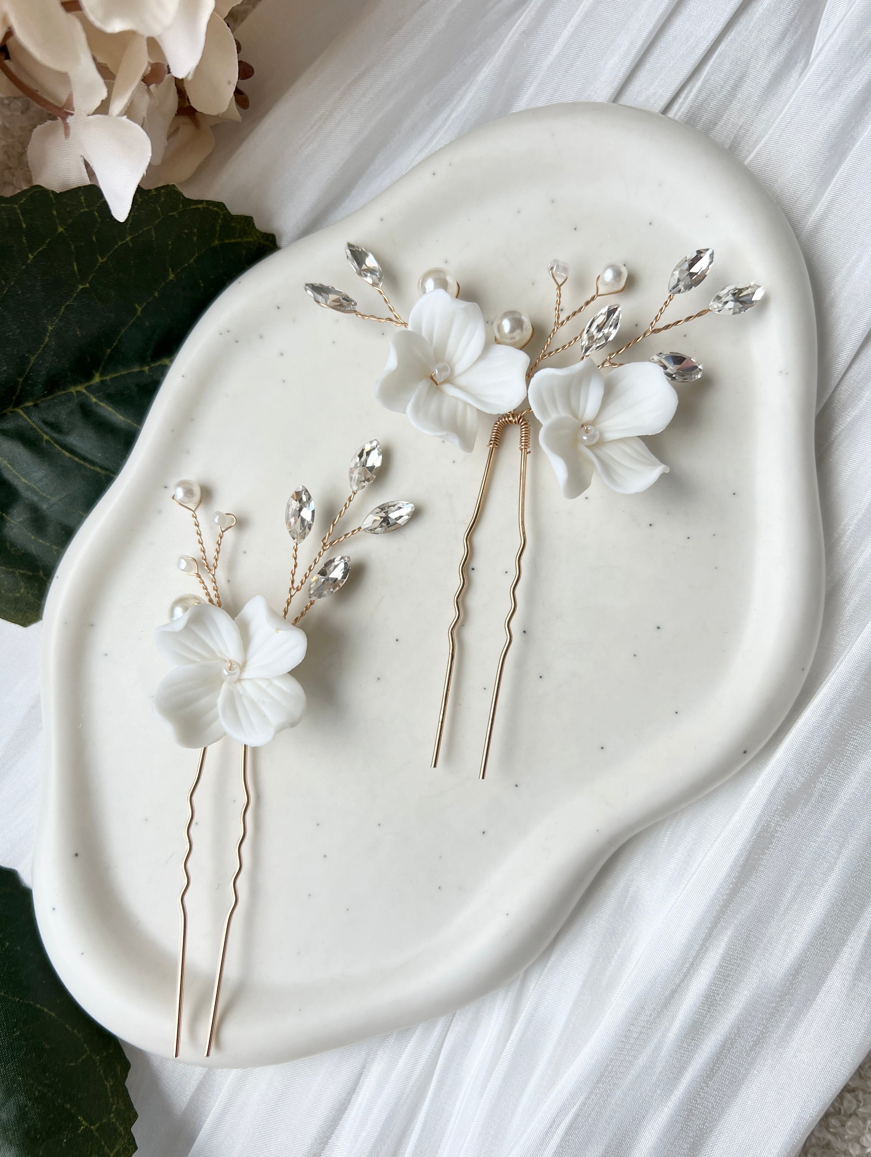 Feine Haarnadeln, Set 2 Stueck, Blumen aus Keramik, feiner goldener Schmuck, Haarschmuck fuer die Brautfrisur, weisser Bluetenschmuck, zarte Perlen und Strasssteine, eleganter Brautschmuck, moderner Perlenschmuck, luxurioeser Brauthaarschmuck, Perlenhaarschmuck, hochwertiger Hochzeitsschmuck, Schmuck Hochzeit, Weddinginspiration